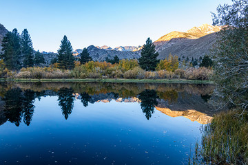 reflecctive mountain lake with pines aspens grass and mountain