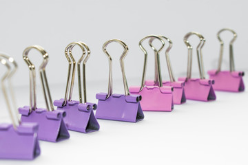 Purple and pink paper clips are separated by color palette, on a white background