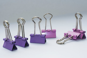 Paper clips standing in a row, one lying on a white background, school days, working with paper