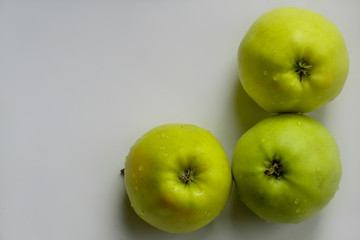 three green apples in the corner of the frame on a white background