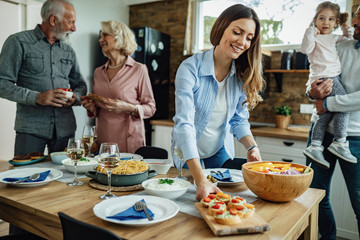 Young happy woman setting dining table for family lunch at home.