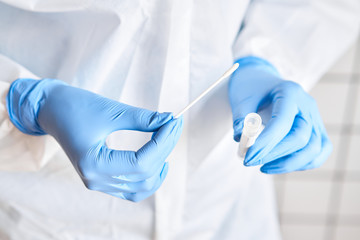 Doctor holding swab test tube for 2019-nCoV analyzing. Coronavirus test. Blue medical gloves and protective face mask for protection against covid-19 virus. Coronavirus and pandemic. © malkovkosta