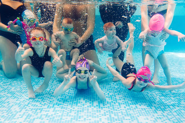 Underwater photo of young friends in swimming pool.