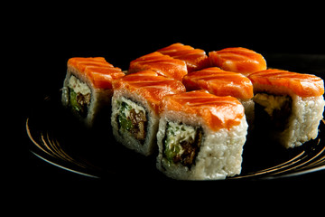 delicious Philadelphia rolls on a black plate and a black wooden background