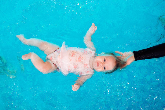 A Swimming Teacher Teaches A Kid To Swim In The Pool.