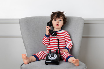 Young child holding vintage phone with funny surprised expression