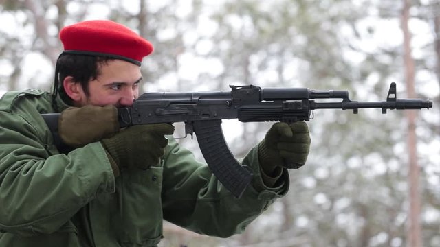 Airsoft. The soldier in red beret aiming their rifle and shooting at the enemy.