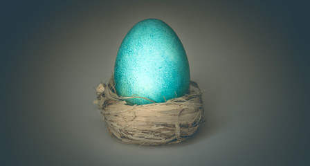 Conceptual, art photo of a blue egg on a dark background. Egg as a symbol of life and easter Easter.