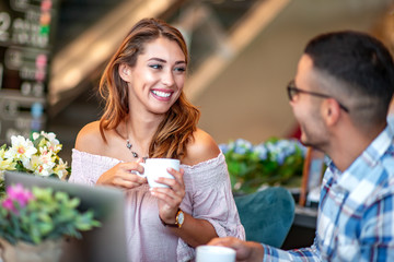 Couple have fun while looking on laptop at cafe