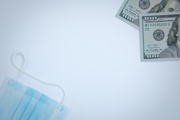 Obraz premium Medical mask and dollar bills in the corners. Copy space. Coronavirus epidemic and economic crisis concept. Top view.