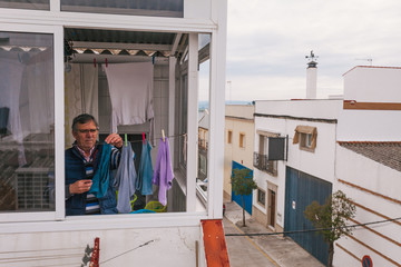 Senior man hanging clothes on the terrace. Homework. Househusband. Selective focus.
