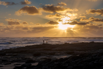 Couple watching a spectacular sunset in a coastal spot