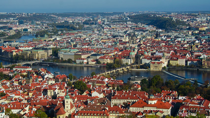 Beautiful view of Prague from the highest part of the city. Sunny weather, bright sky and river. Tile roofs glisten in the sun.