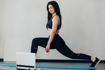 Home training, fitness, motivation concept. Young fit woman doing sport exercises with online guide...