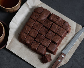 Dessert chocolate biscuit cut into cubes with coffee on a dark background top view
