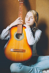 Stay Home Stay Safe. Young woman sitting in room on floor and playing guitar at home. Teen girl...