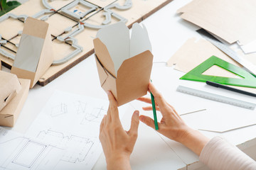 Box maker holding square food container in her fingers