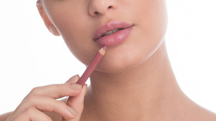 Unrecognizable woman applying nude lip liner in studio