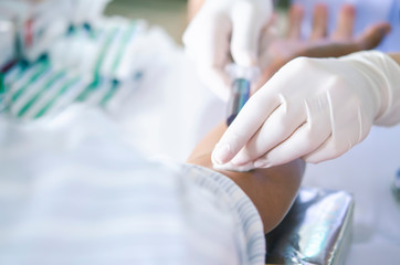 Soft focus on the hands of the doctor drawing a blood sample from the arm for blood test finds...