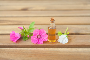 Fototapeta na wymiar mallow essential oil in beautiful bottle on wooden background