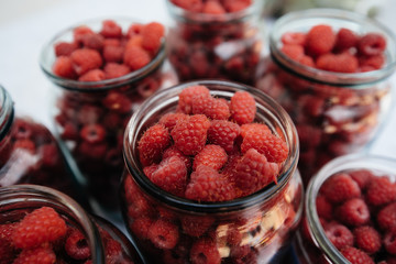Fresh, ripe raspberries in small jars close-up