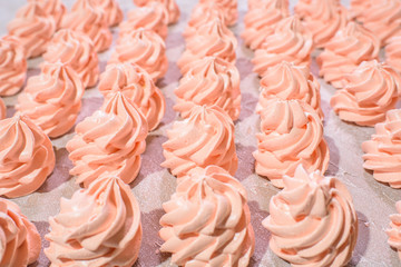 Delicious pink freshly made meringues lined up symmetrically on a concrete background. Pattern.