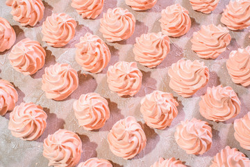 Delicious pink freshly made meringues lined up symmetrically on a concrete background. Pattern.