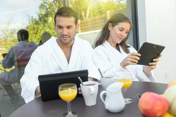 Happy young couple in bathrobes are surfing on the web outdoors