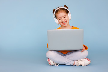 Cheerful girl in headphones using laptop