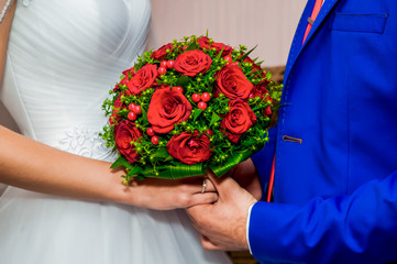 The bride and groom hold a wedding bouquet together