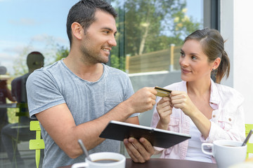 Couple talking and buying something online with a tablet outdoors