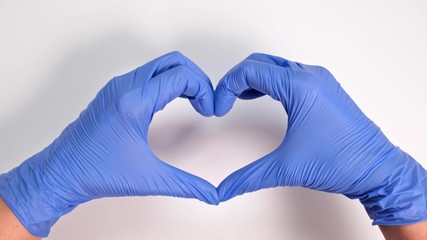 Fototapeta premium Hands of a doctor or nurse in medical gloves depict a heart on a white background, caring doctor and medicine concept
