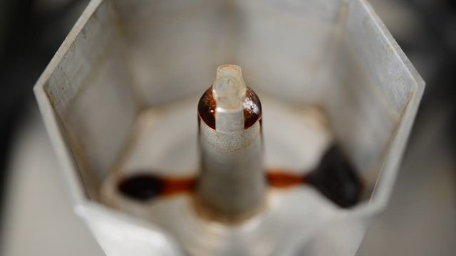 Macro close-up of a boiling espresso that comes out of an old moka, progressive focus. The first part.