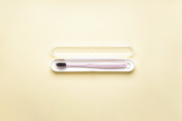 Toothbrush in a case on a yellow background, flat lay.