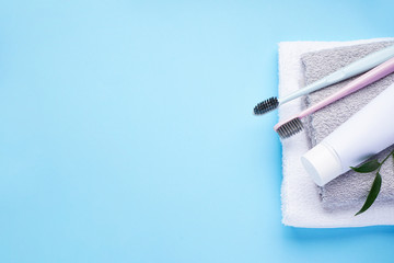 Two toothbrushes with towels on a blue background with space for text. Flat lay