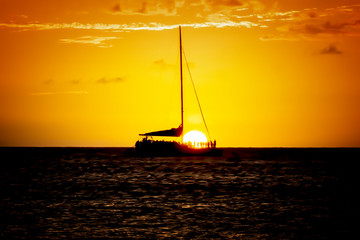 Sunset Sail with Sun Dropping Below Horizon and Boat