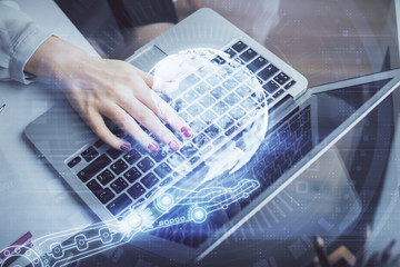 Double exposure of woman hands working on computer and world map hologram drawing. International...