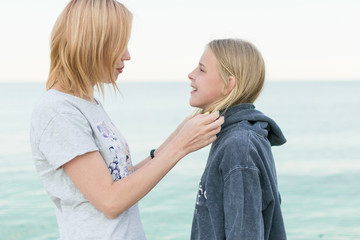 Mother and teenage daughter are smiling on the beach.Mutual understanding between the parent and the child.