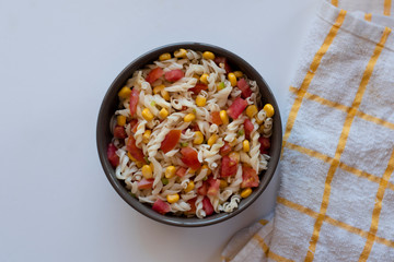 Pasta salad with yogurt and tomato sauce, corn and green onion on white background
