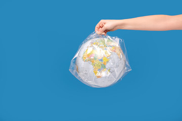 Hand holding a world globe wrapped in plastic.