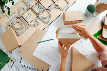 Woman holding box with a hole above her workplace