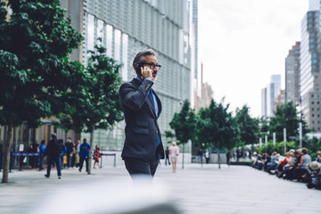 Mature businessman calling by smartphone in city