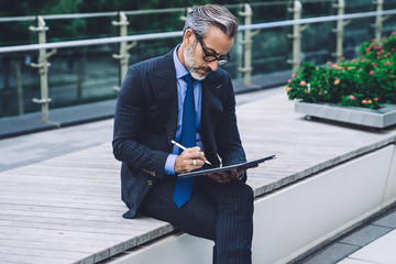 Mature businessman using tablet with stylus pen on bridge