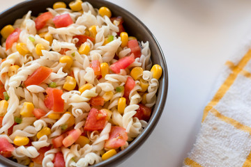 Pasta salad with yogurt and tomato sauce, corn and green onion on white background