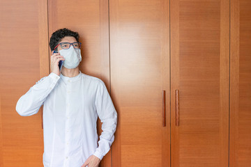 Latin wearing mask and talking on cell phone in his room during pandemic covid-19.