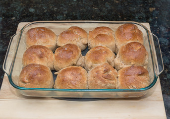 Home made baked sweet golden buns sitting on a wooden cutting board on a marble counter