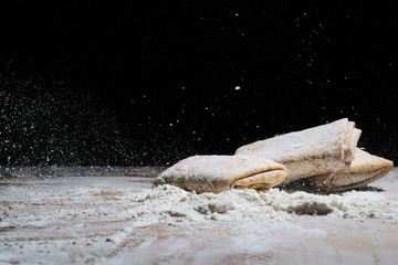 pancakes made of dough in flour on a dark background close up
