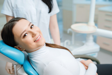 Patient in dental chair. Beautiful young woman having dental treatment at dentist's office. Healthy...