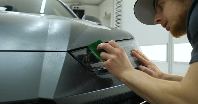 Close up of paint protection film installation on modern luxury car. PPF is polyurethane film that wrap car paint to protect paint surface from stone chips, bug splatter, and abrasion.