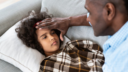 Virus outbreak. Senior African American man touching his granddaughter's forehead, checking fever...